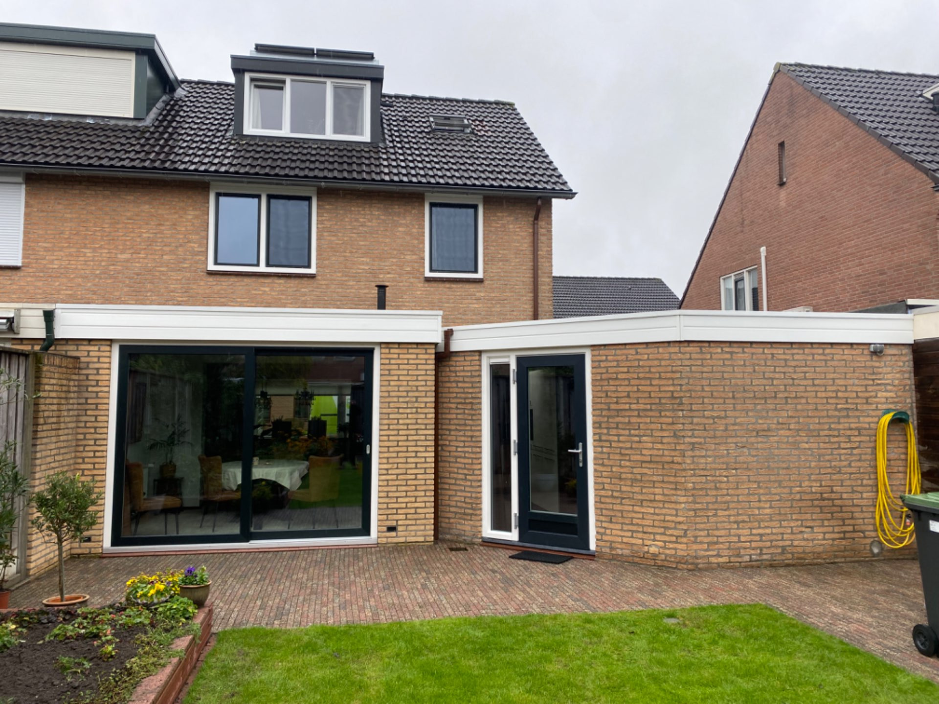 Woning renoveren met een schuifpui bij de achtertuin voor een betere toegang, meer lichtinval en verbeterde isolatie. Kunststof gevelbekleding